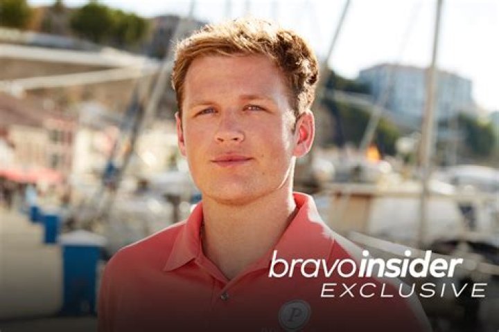 Tom Pearson smiles on boat in orange polo